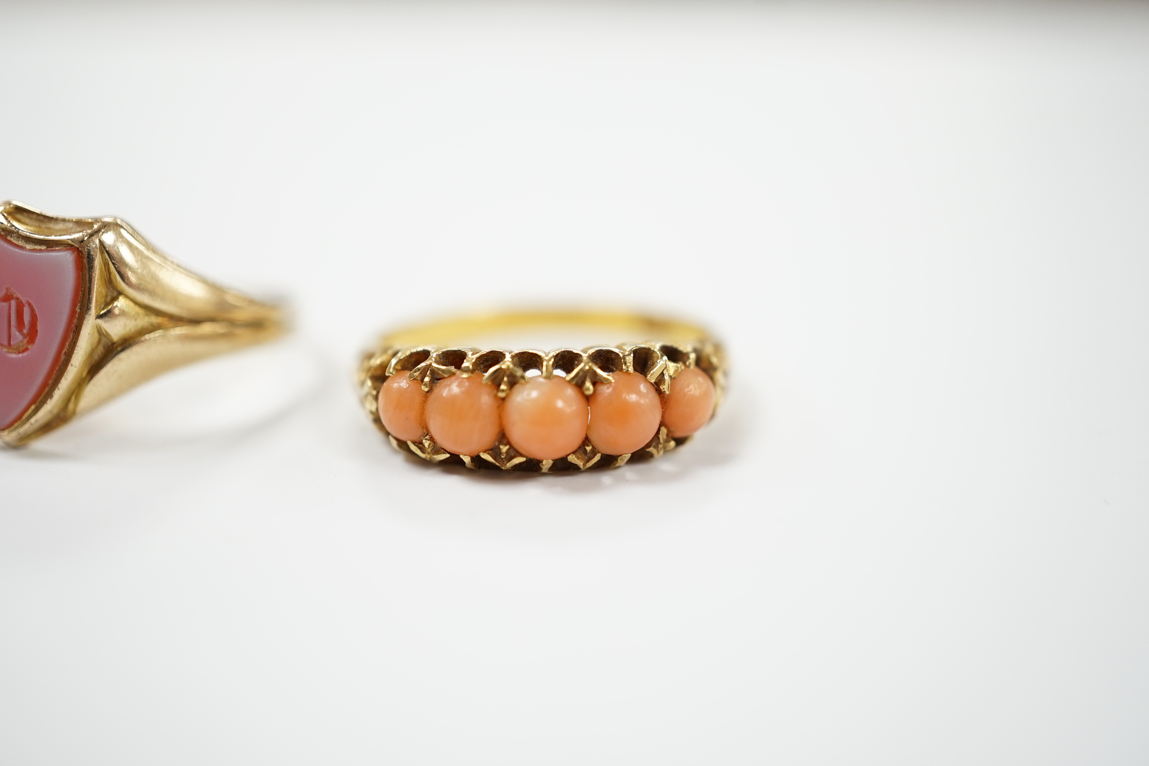 An early 20th century 18ct and graduated five stone split coral bead set half hoop ring, size O and a Victorian 12ct gold and sardonyx set shield shaped signet ring, size Q.